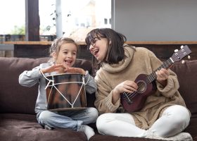 Young mother and daughter play musical instruments at home. Mom plays with her daughter at home. Lessons on a musical instrument. Children's development and family values. The concept of children's friendship and family.